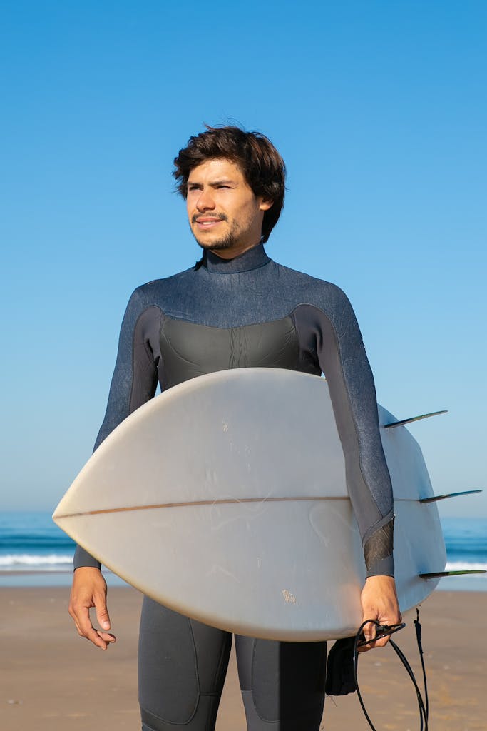 Man in Full Body Swimwear Holding Surfboard